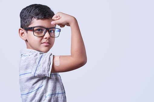 protein powder for kids - a little boy showing off his muscles. 